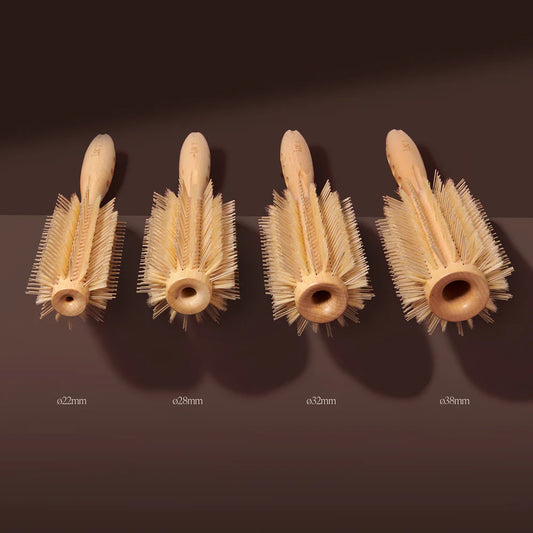 Four wooden brush heads with varying diameters on a dark brown background