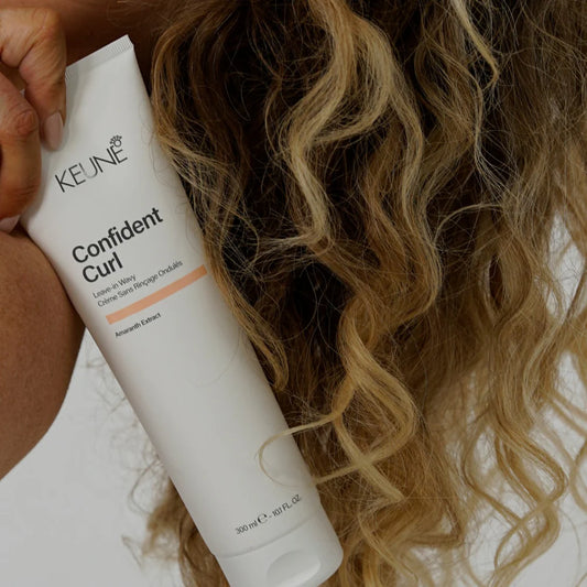 Person holding a Keune Confident Curl product with curly hair