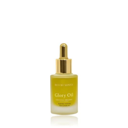 A bottle of ECO BY SONYA Glory Oil with a gold dropper cap and a frosted glass bottle showing a yellow-green oil inside, set against a plain white background.