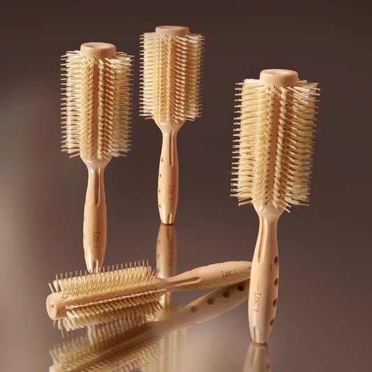 Set of four wooden hairbrushes with bristle heads on a reflective surface.