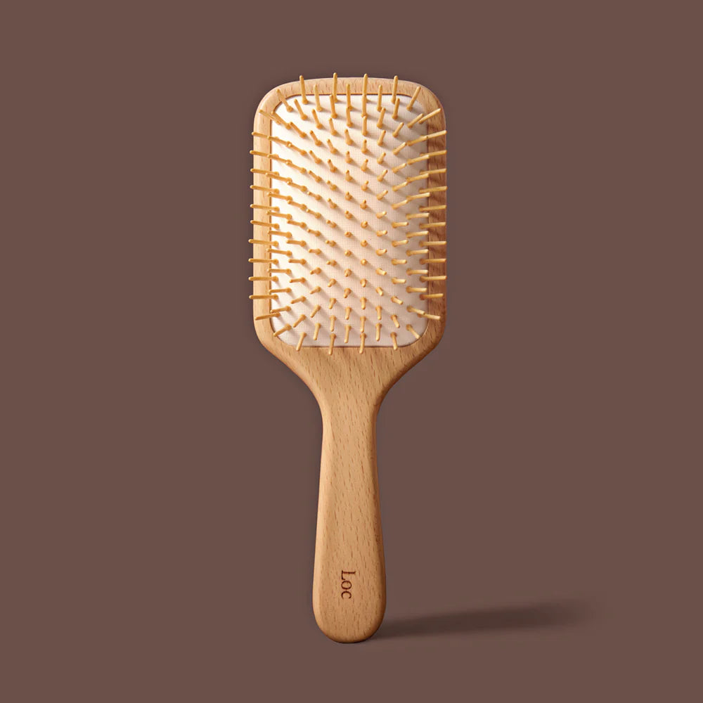 Wooden paddle hairbrush on a brown background