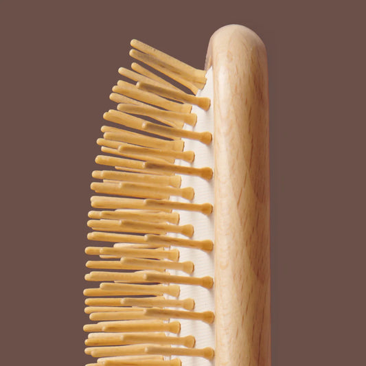 Wooden hairbrush with wooden handle on a brown background