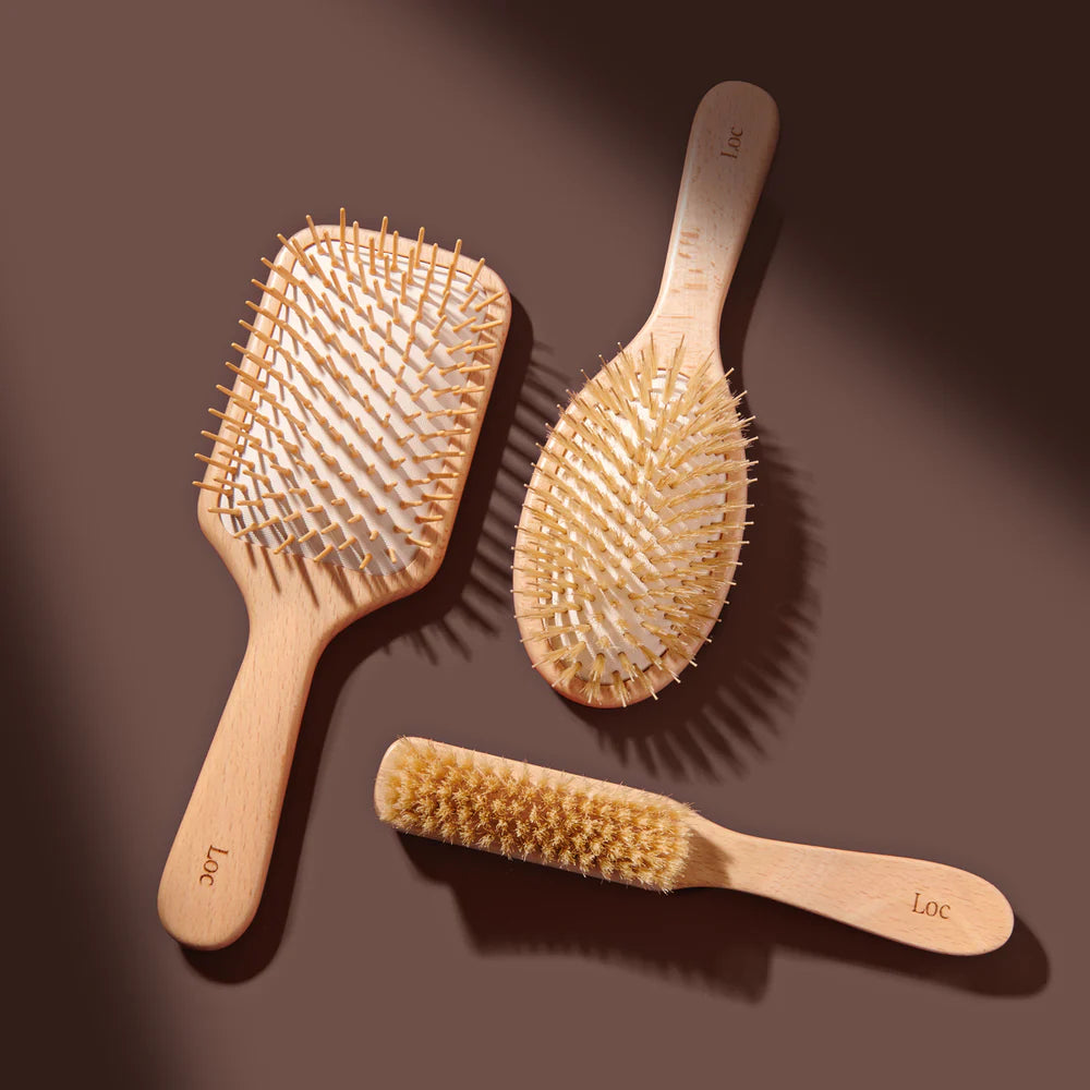 Three wooden hairbrushes on a brown background