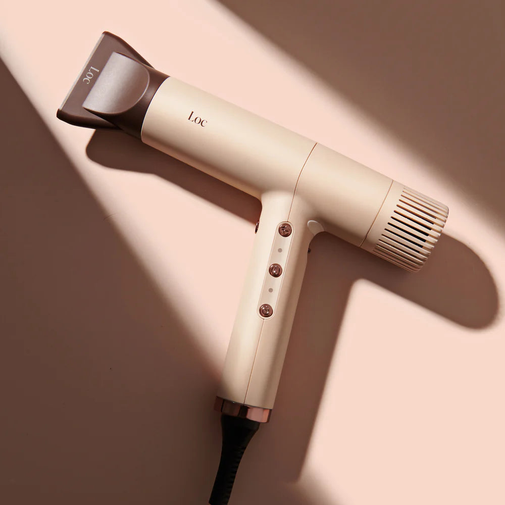 Beige hair dryer with black nozzle on a beige background