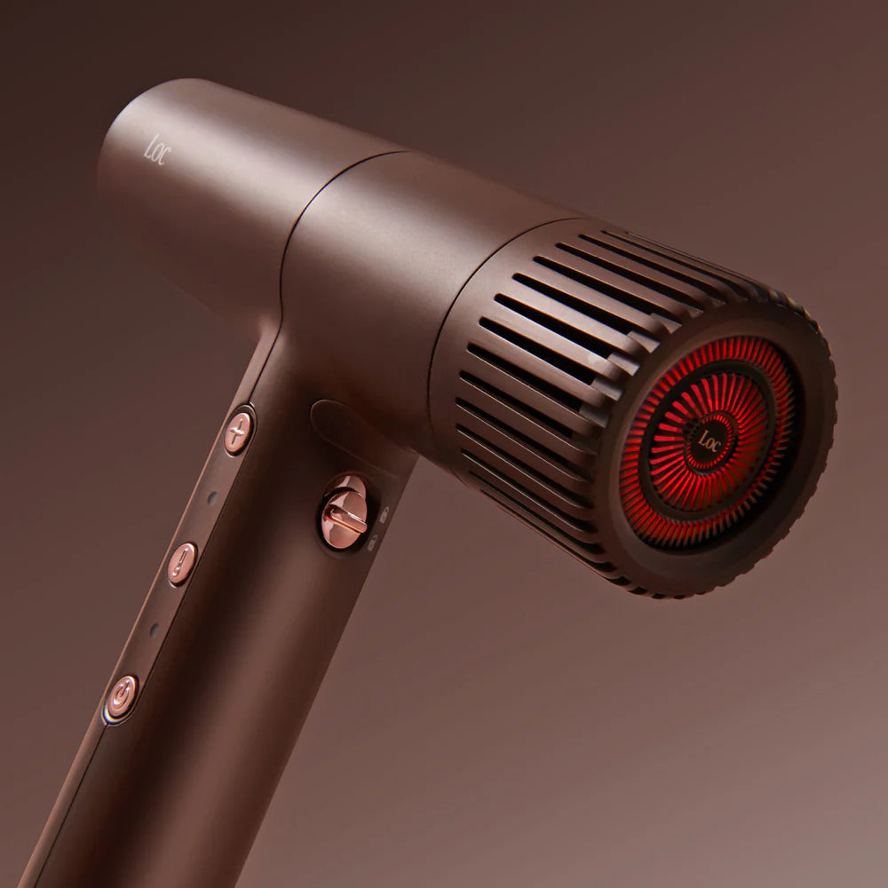 Hair dryer with a metallic finish and red interior on a brown background