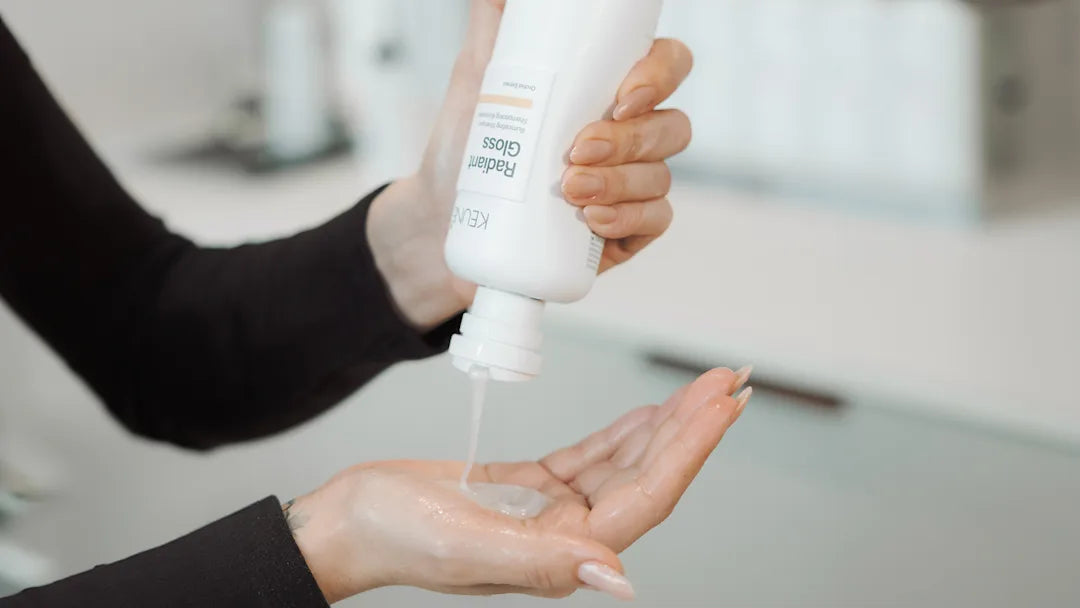 Person holding a white bottle with a pump dispenser over another hand.