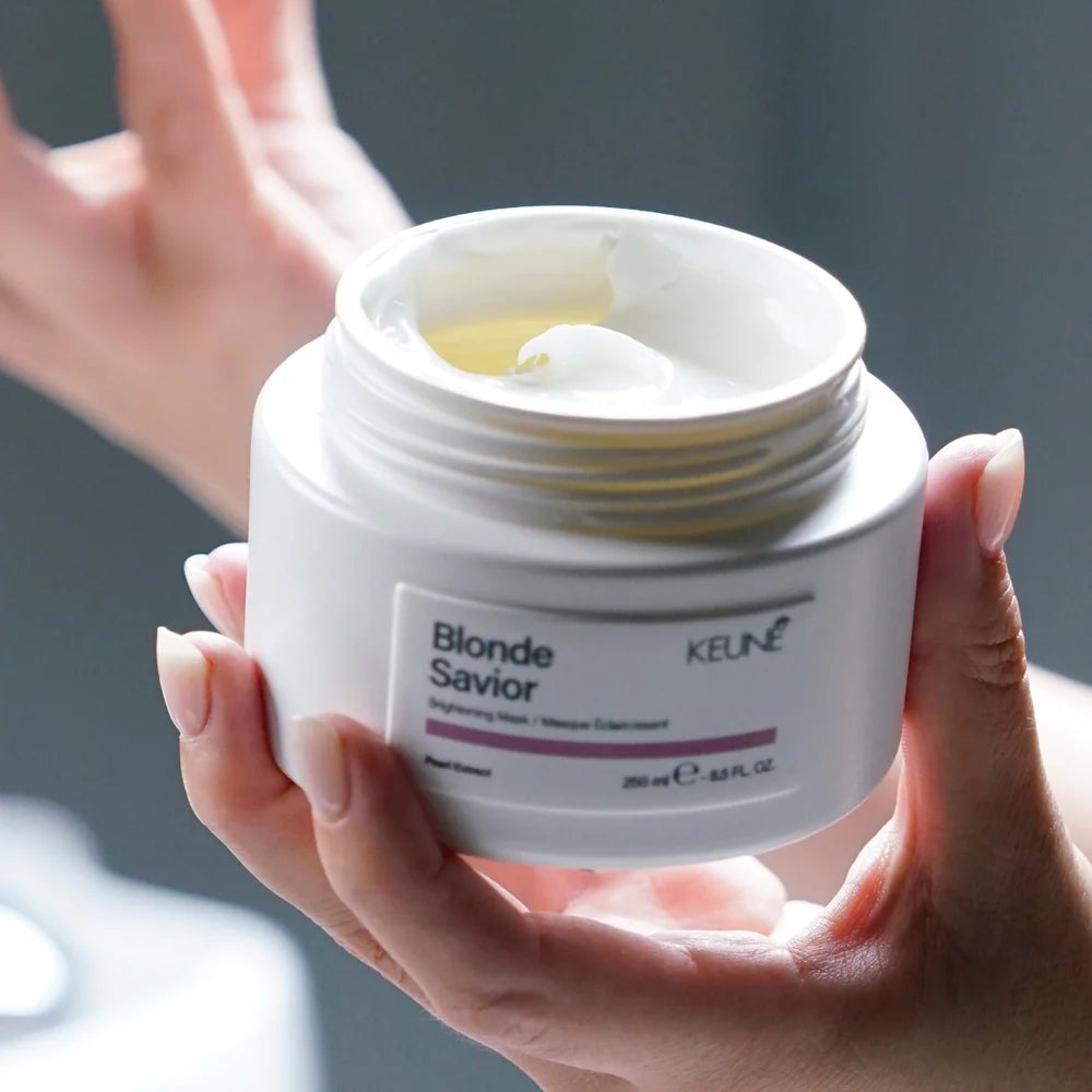 Person holding a jar of Blonde Savior KEUNE hair mask against a neutral background
