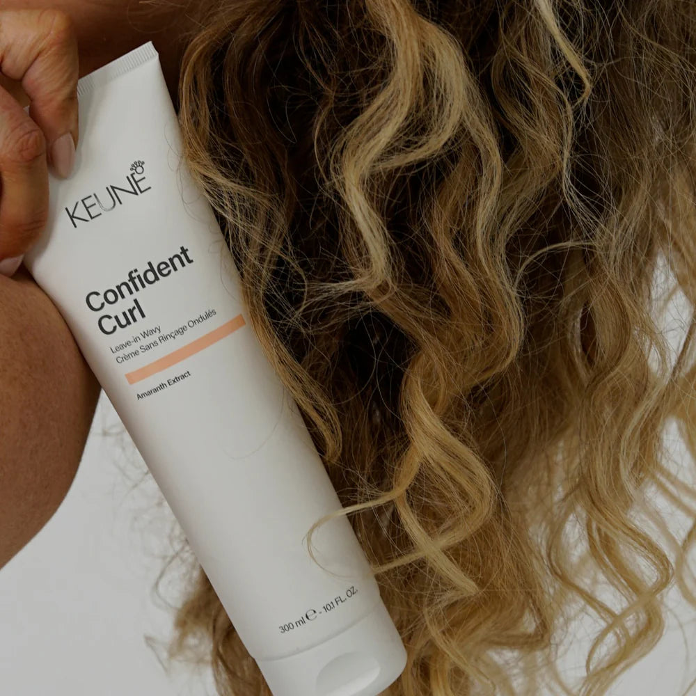 Person holding a Keune Confident Curl product with curly hair