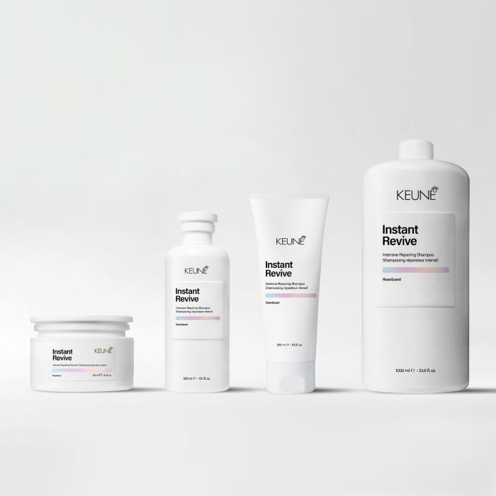 Four white KEUNE haircare containers arranged in a row on a light gray studio background: a small jar, a small bottle, a squeeze tube, and a large bottle, all labeled Instant Revive.