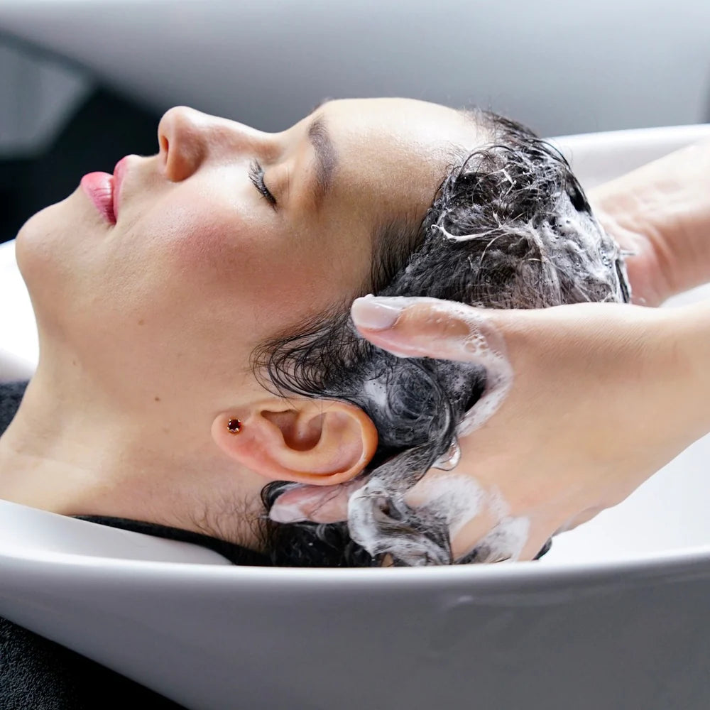 Person getting a hair wash with soapy water in a salon setting